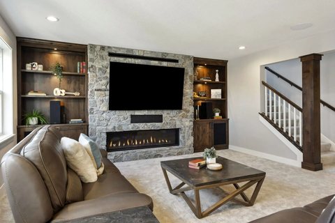 Finished basement with a stone fireplace, built-ins, and a media wall — MDR Design-Build-Remodel