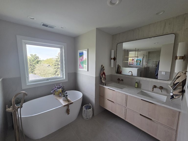 Master bath with a freestanding tub, double vanity, and a bright window — MDR Design-Build-Remodel